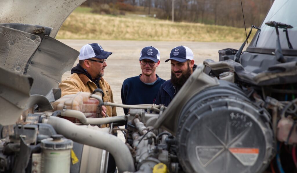 Students looking at truck engine.